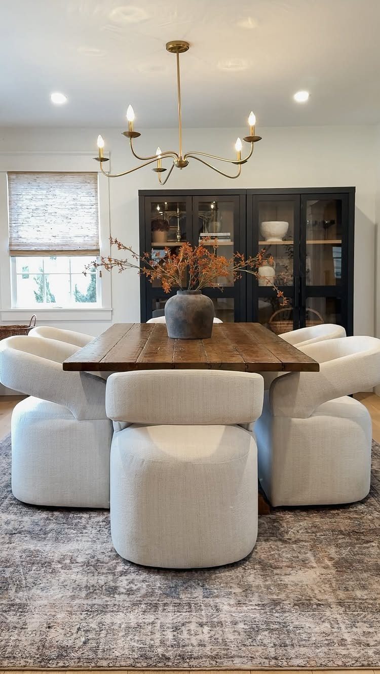 11 Rustic Modern Dining Room Ideas with Real Character 1 Gold chandelier hanging over a wooden dining table with white upholstered chairs.
