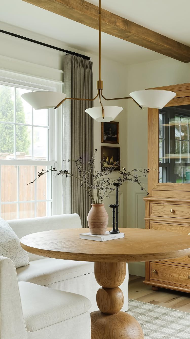 12 Small Dining Area Design Ideas That Maximize Space 1 Round light-wood dining table with white banquette seating in a bright, airy room.