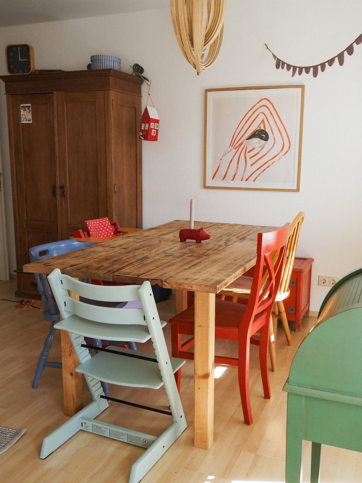 12 Small Dining Area Design Ideas That Maximize Space 10 Wooden dining table surrounded by colorful mismatched chairs in a bright room.