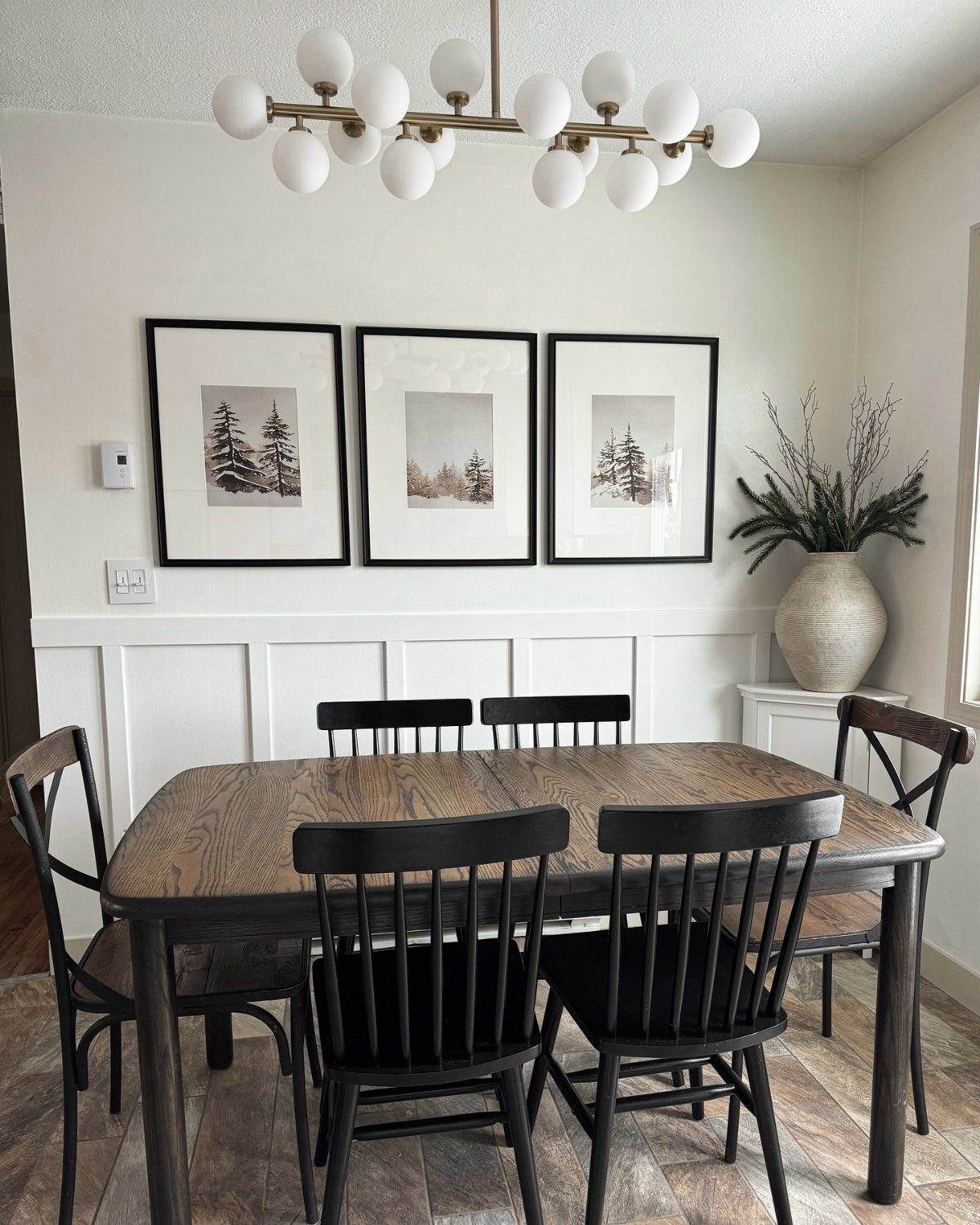 12 Small Dining Area Design Ideas That Maximize Space 12 Wooden dining table with black chairs and three framed landscape prints on white wall.