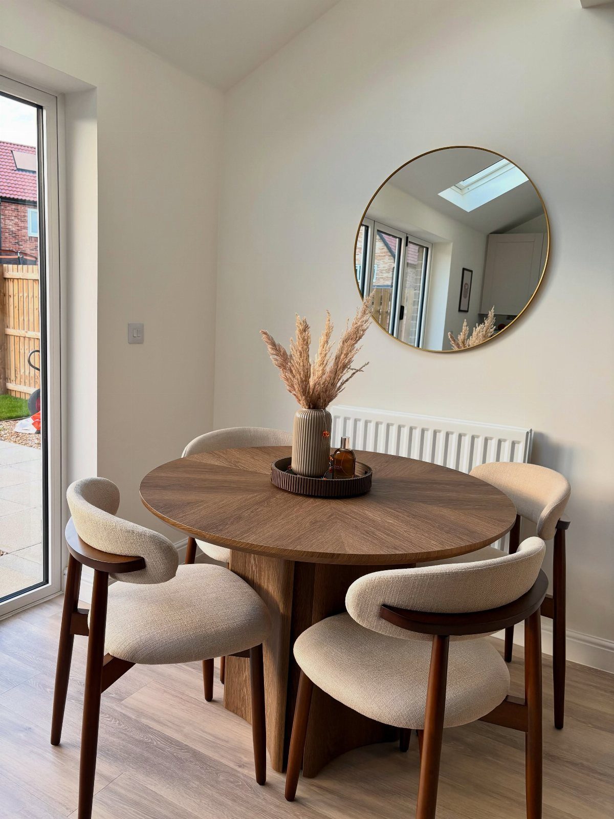 12 Small Dining Area Design Ideas That Maximize Space 3 Round wooden dining table with cream chairs and a large circular wall mirror.