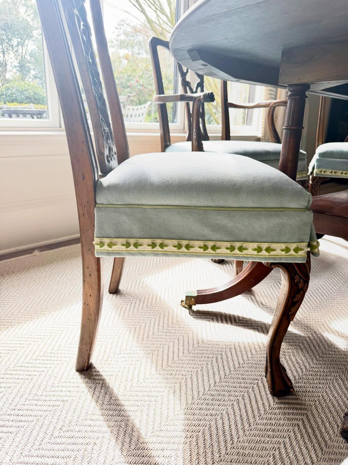 Dining chair with blue upholstery sitting on a beige chevron patterned rug.