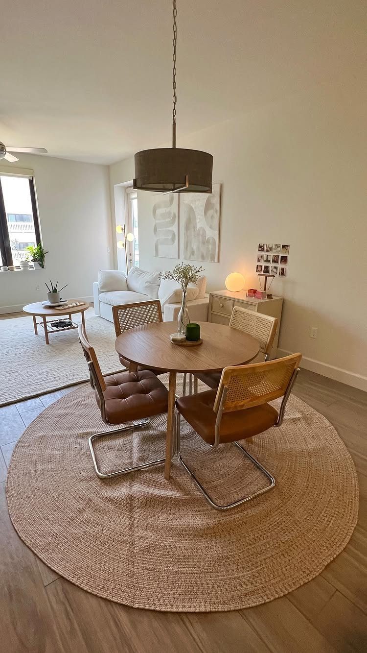 Round woven rug under a circular wooden dining table with brown chairs