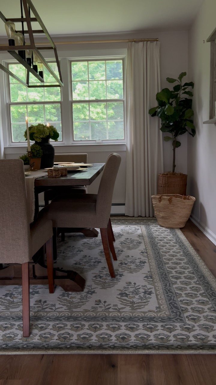 Dining table and chairs placed on a patterned rug in a bright room.