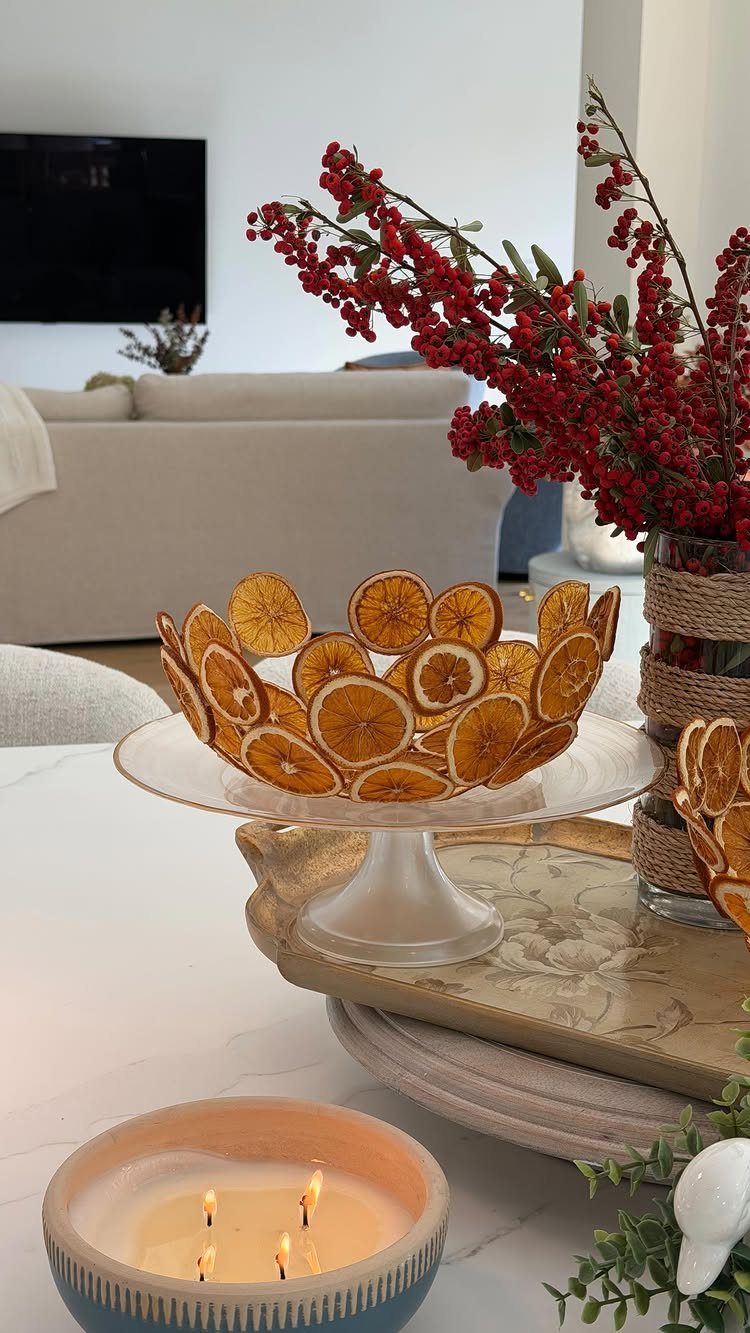 8 Small Dining Table Decor Ideas for Every Style 7 Dried orange slices in a bowl on a cake stand with red berries.