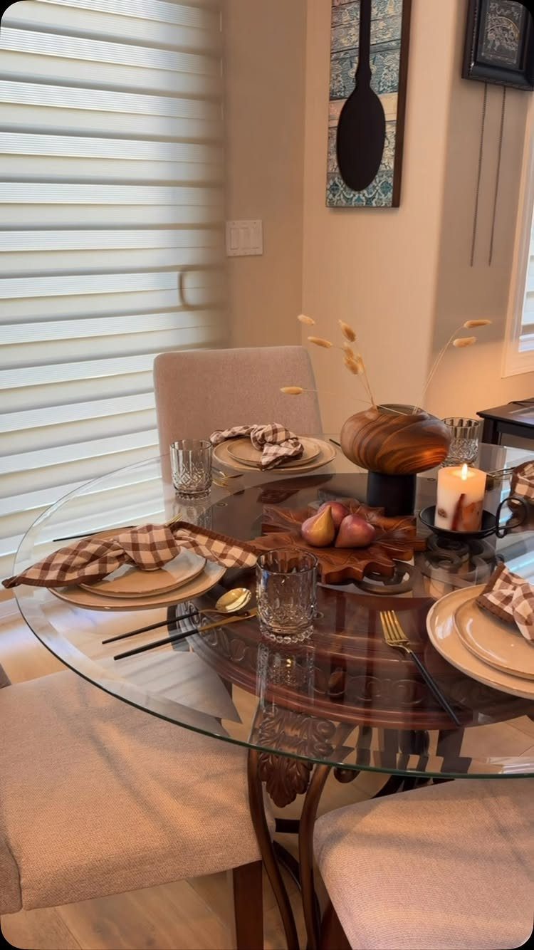 8 Small Dining Table Decor Ideas for Every Style 5 Round glass dining table with place settings, a wooden bowl, and a lit candle.