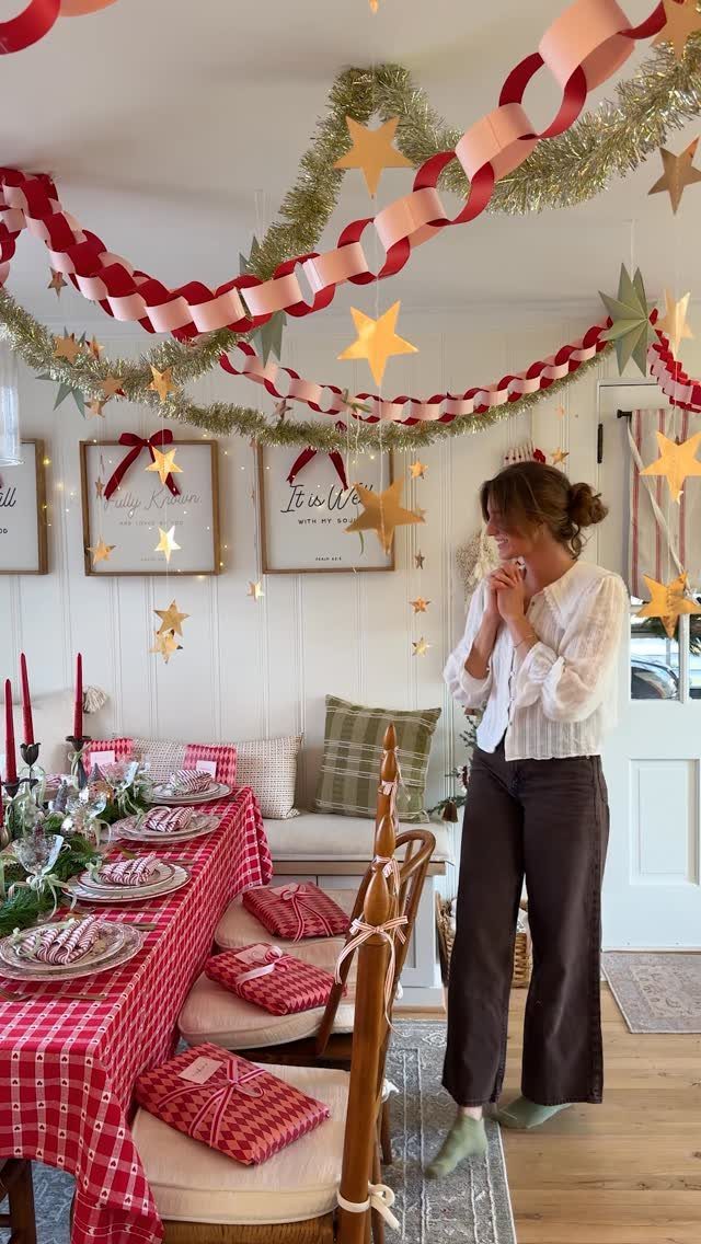 Woman standing in a festive room with red checkered table and ceiling decorations.