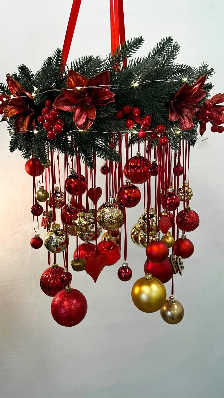 Hanging evergreen wreath with red and gold ornaments suspended by red ribbons.