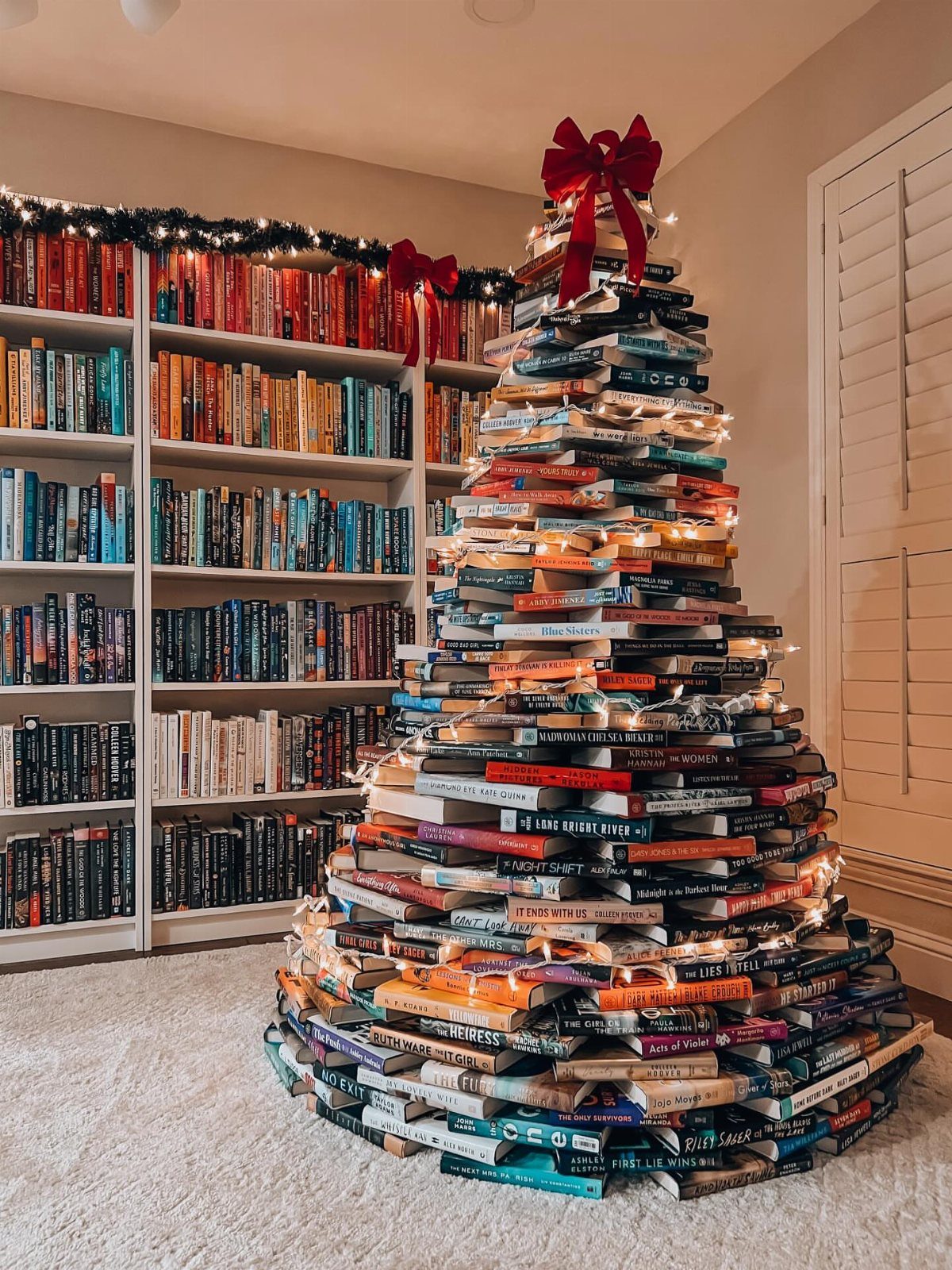 Christmas tree made of stacked books with fairy lights and a red bow.