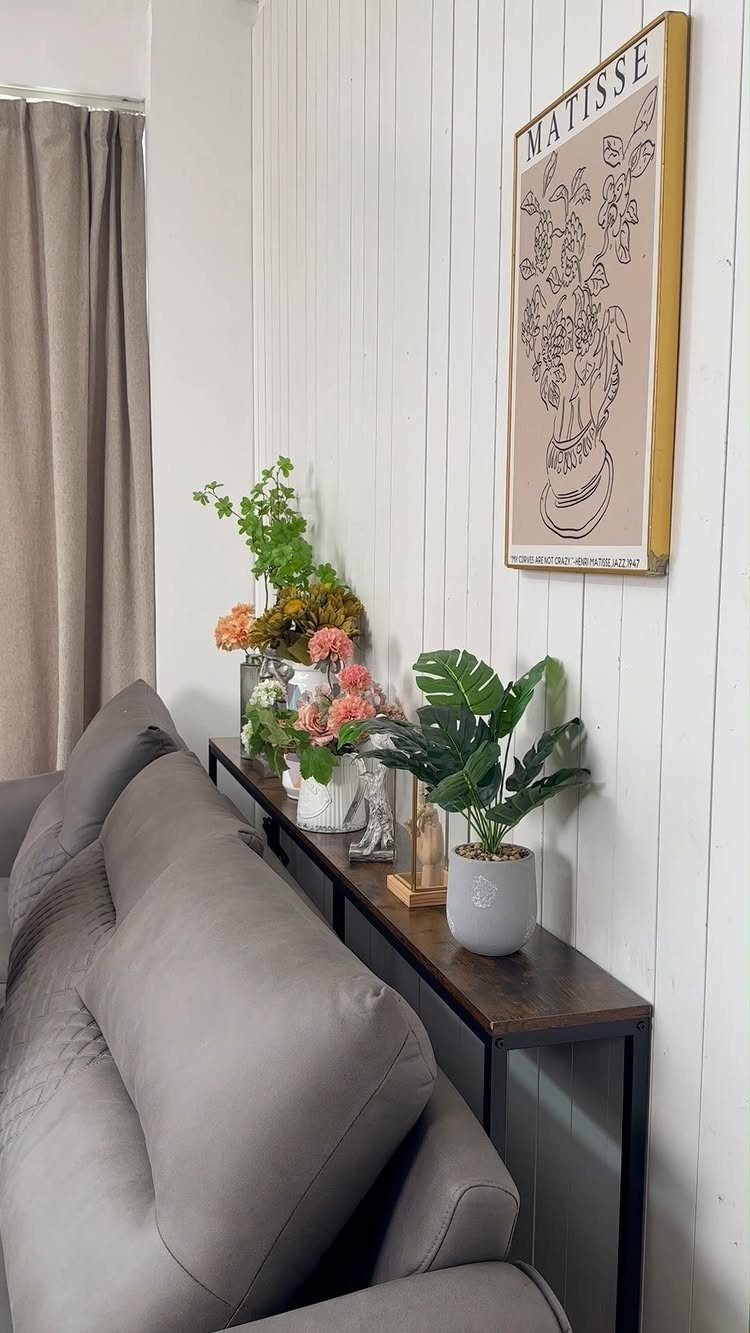 15 Small Living and Dining Room Ideas That Maximize Space 9 Slim dark wood console table behind a grey sofa with plants and wall art.