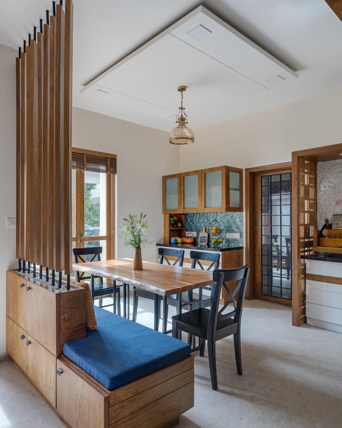 15 Small Living and Dining Room Ideas That Maximize Space 11 Wooden dining table and blue banquette seating separated by a vertical slat partition.