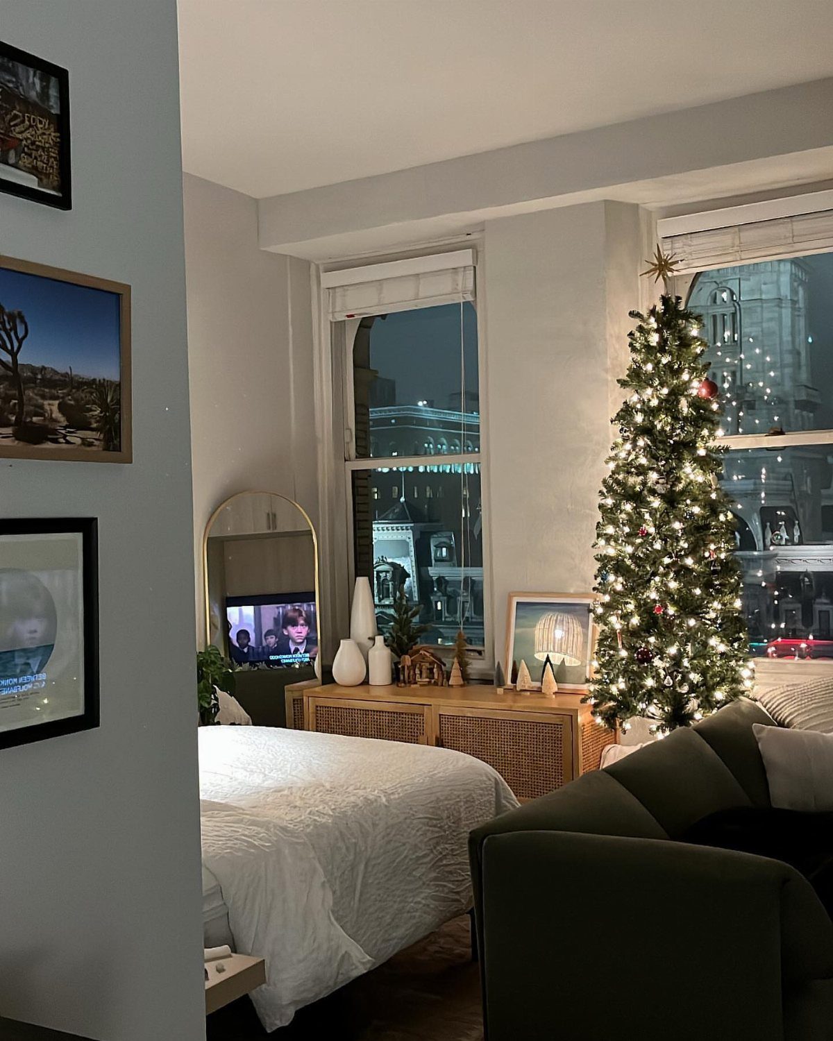 12 Studio Apartment Christmas Decor Ideas That Save Space 8 Christmas tree with lights in a small studio apartment next to a bed.