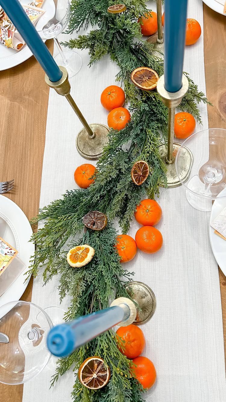 12 Studio Apartment Christmas Decor Ideas That Save Space 6 Evergreen garland with oranges and blue candles on a white table runner.