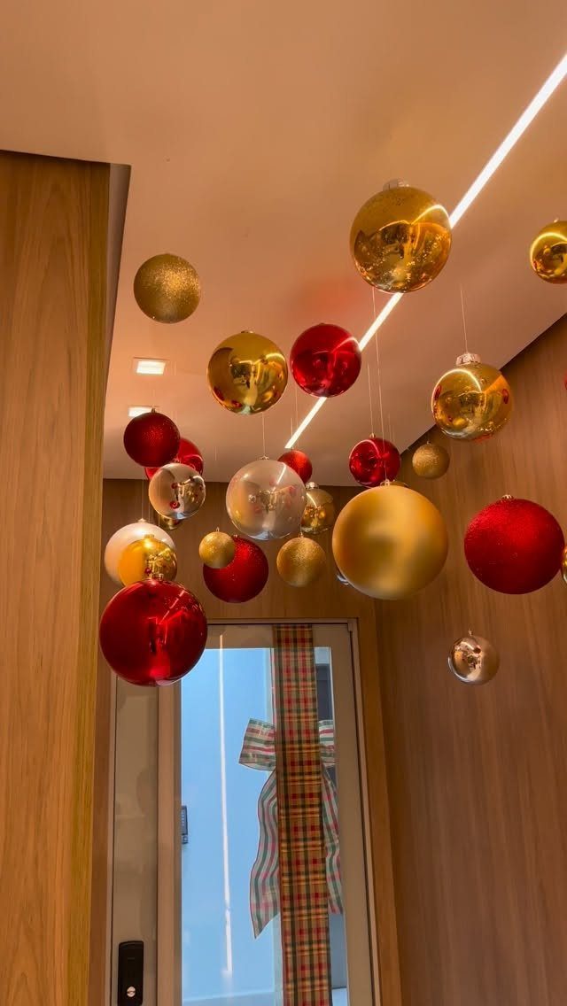 12 Studio Apartment Christmas Decor Ideas That Save Space 9 Red, gold, and silver Christmas ornaments hanging from a ceiling in a modern room.
