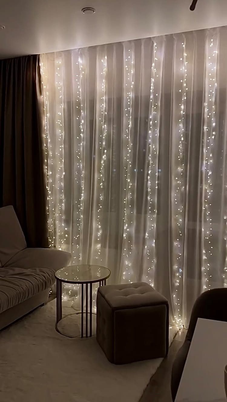 12 Studio Apartment Christmas Decor Ideas That Save Space 4 String lights glowing behind sheer white curtains in a cozy living room setting.