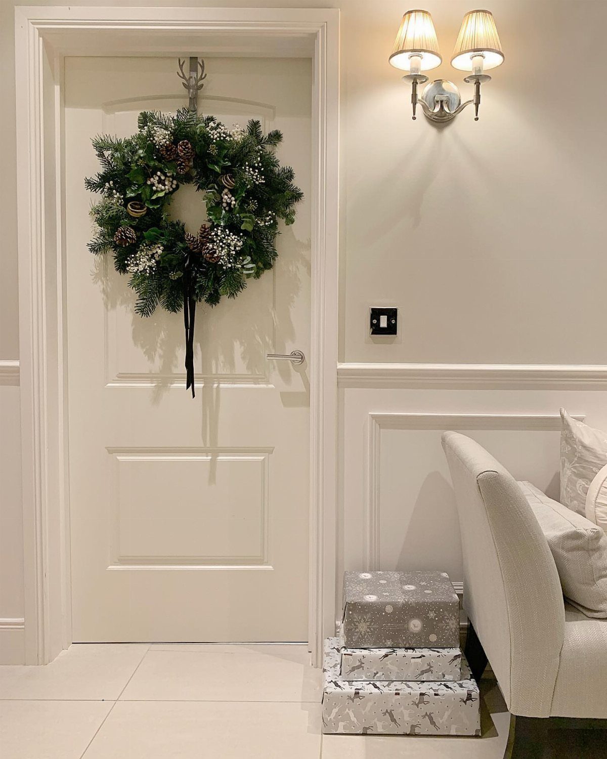 12 Studio Apartment Christmas Decor Ideas That Save Space 1 Green Christmas wreath hanging on a white interior door next to wrapped gifts.
