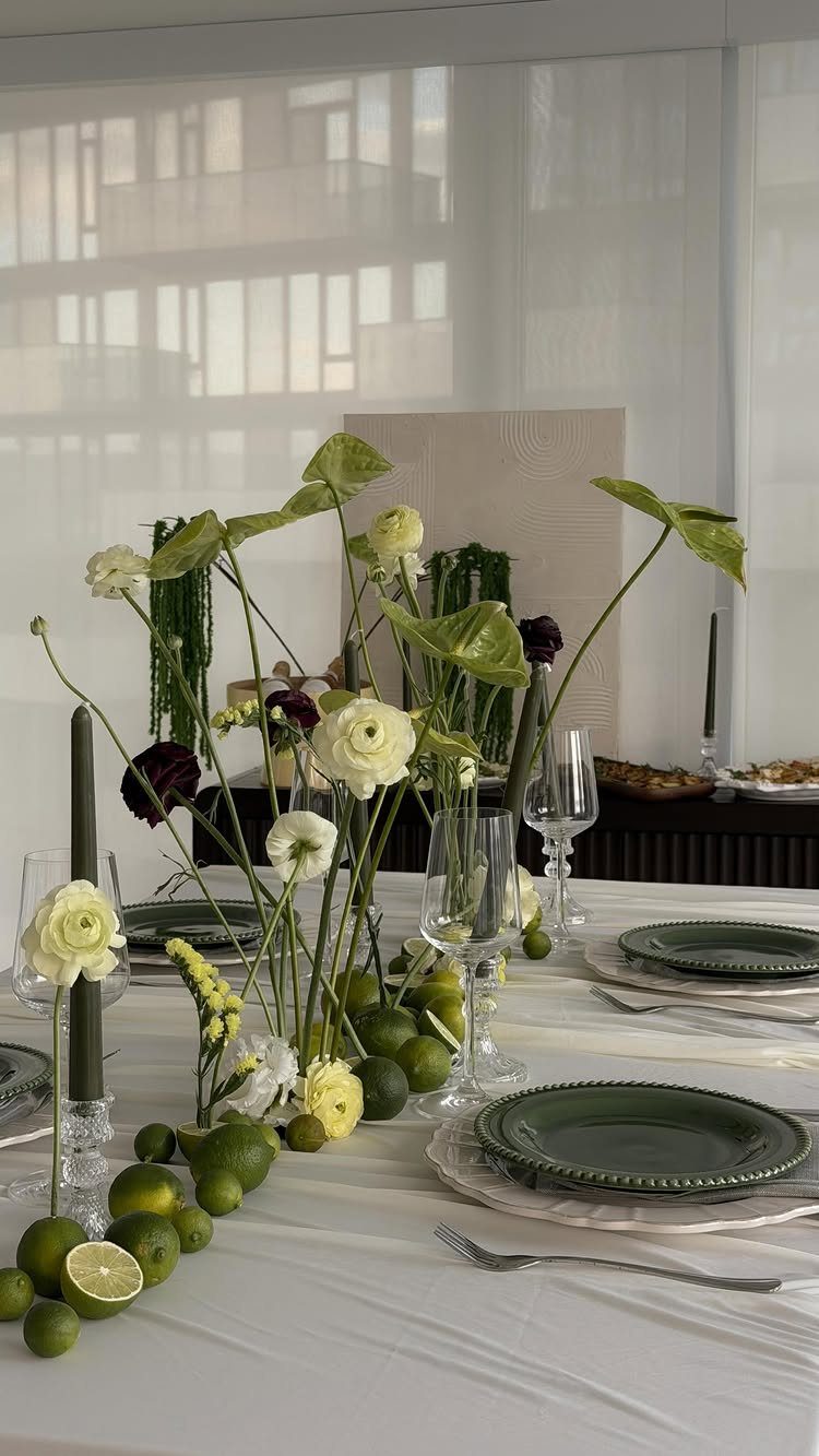 7 Table Centerpiece Ideas for Christmas That Feel Fresh 2 Dining table centerpiece with white flowers and scattered green limes on white tablecloth.