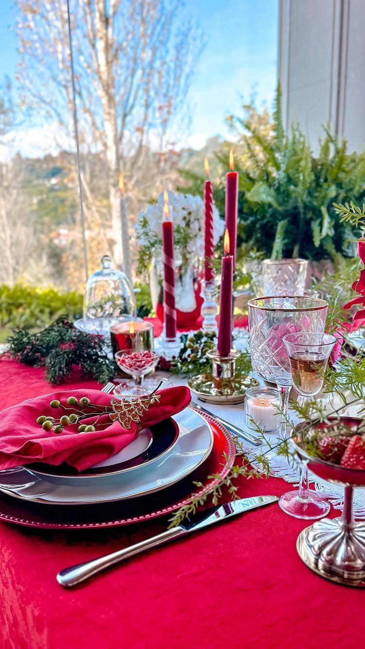 7 Table Centerpiece Ideas for Christmas That Feel Fresh 5 Elegant Christmas table setting with red candles, white flowers, and red tablecloth.