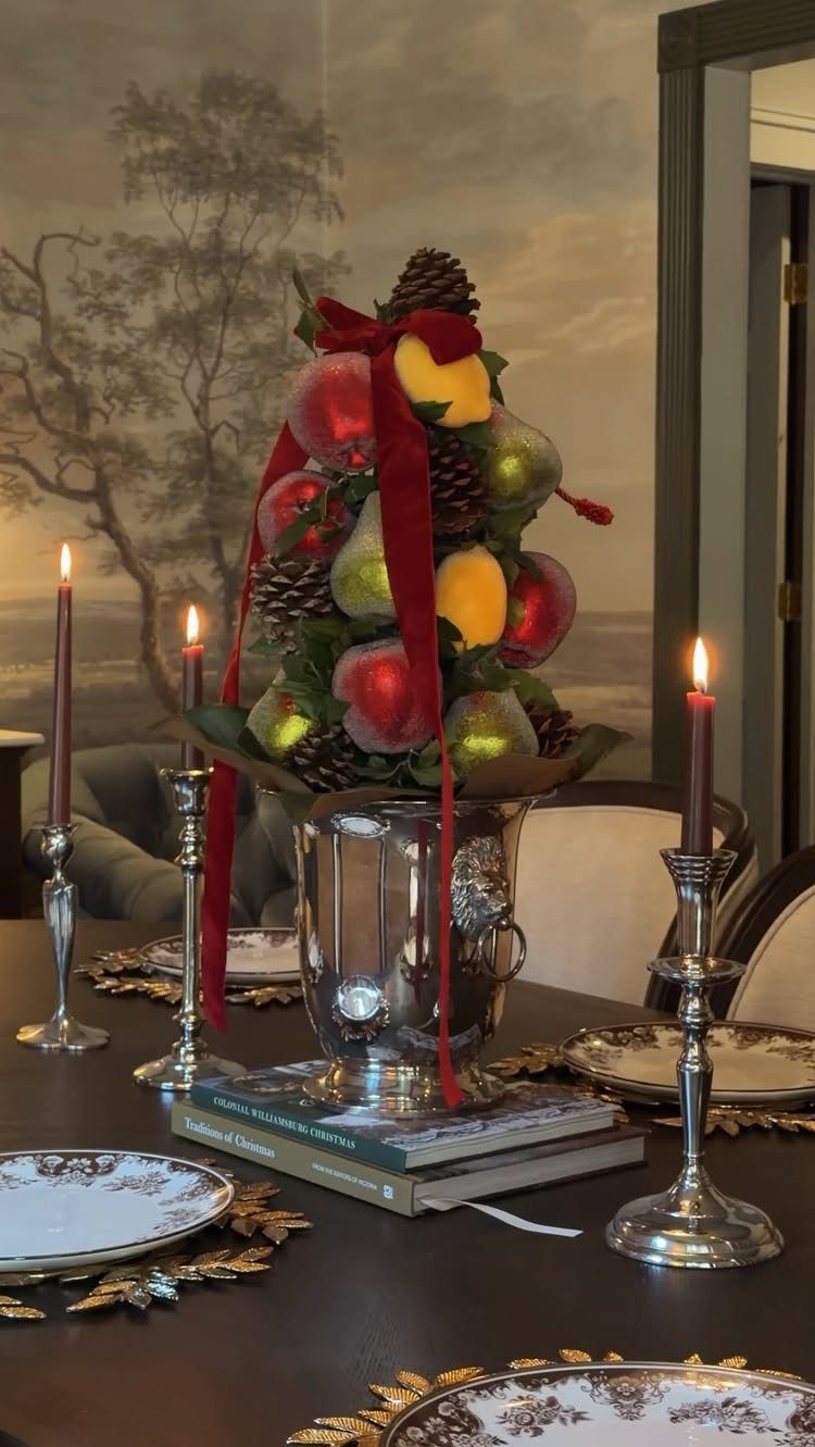 7 Table Centerpiece Ideas for Christmas That Feel Fresh 4 Sugared fruit and pinecone centerpiece in a silver bowl on a dining table.