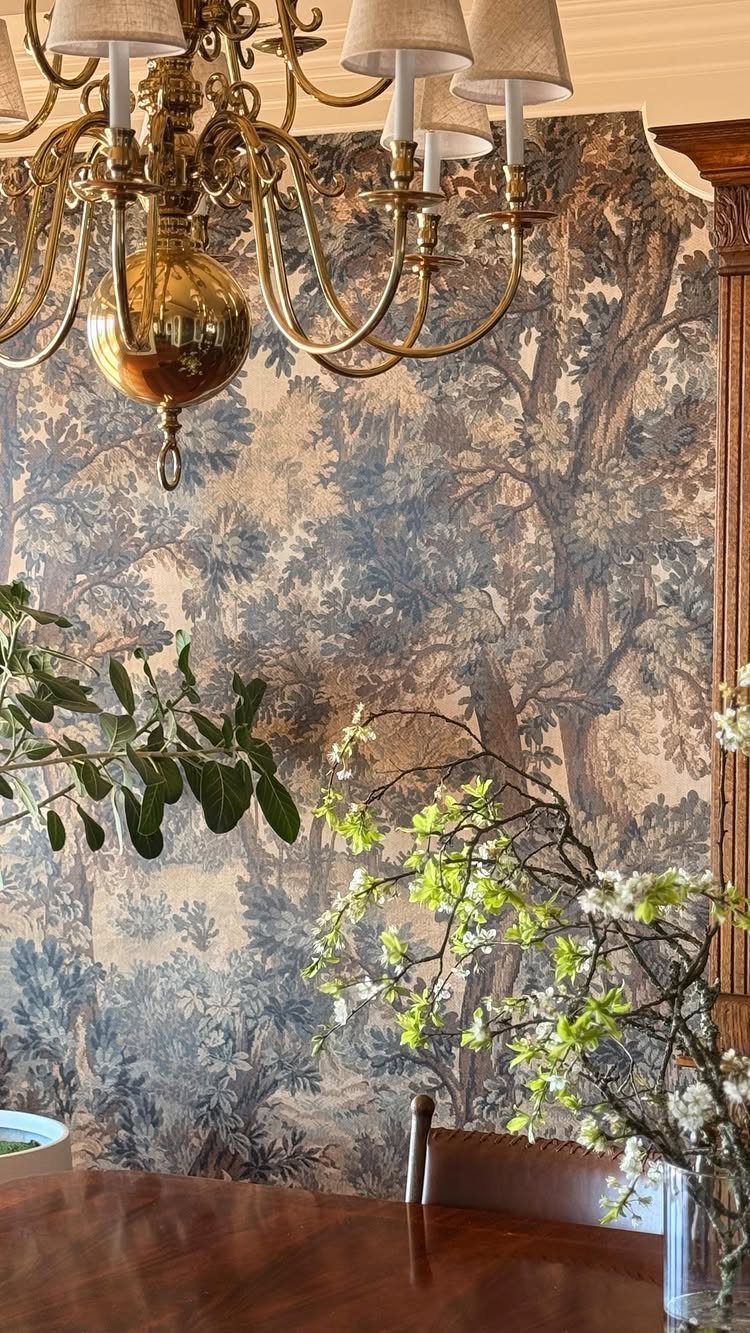 Traditional Modern Dining Room Ideas: 20 Ways to Blend Styles 10 Landscape patterned wallpaper in blue and brown with a gold chandelier and plants.