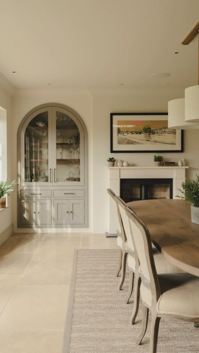 Traditional Modern Dining Room Ideas: 20 Ways to Blend Styles 15 Dining room with wooden table, upholstered chairs, and a built-in arched glass cabinet.