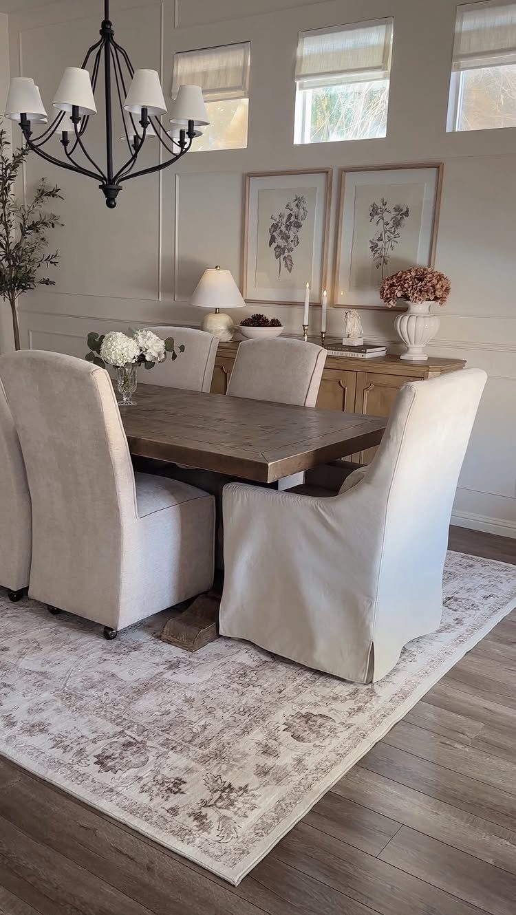 Traditional Modern Dining Room Ideas: 20 Ways to Blend Styles 17 Wooden dining table with cream slipcovered chairs on a patterned rug in a bright room.