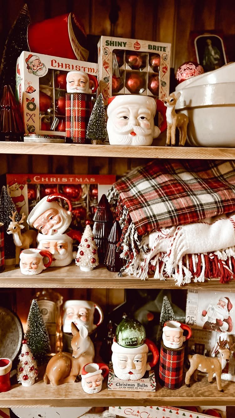Vintage Christmas decorations including Santa mugs and plaid blankets on wooden shelves.