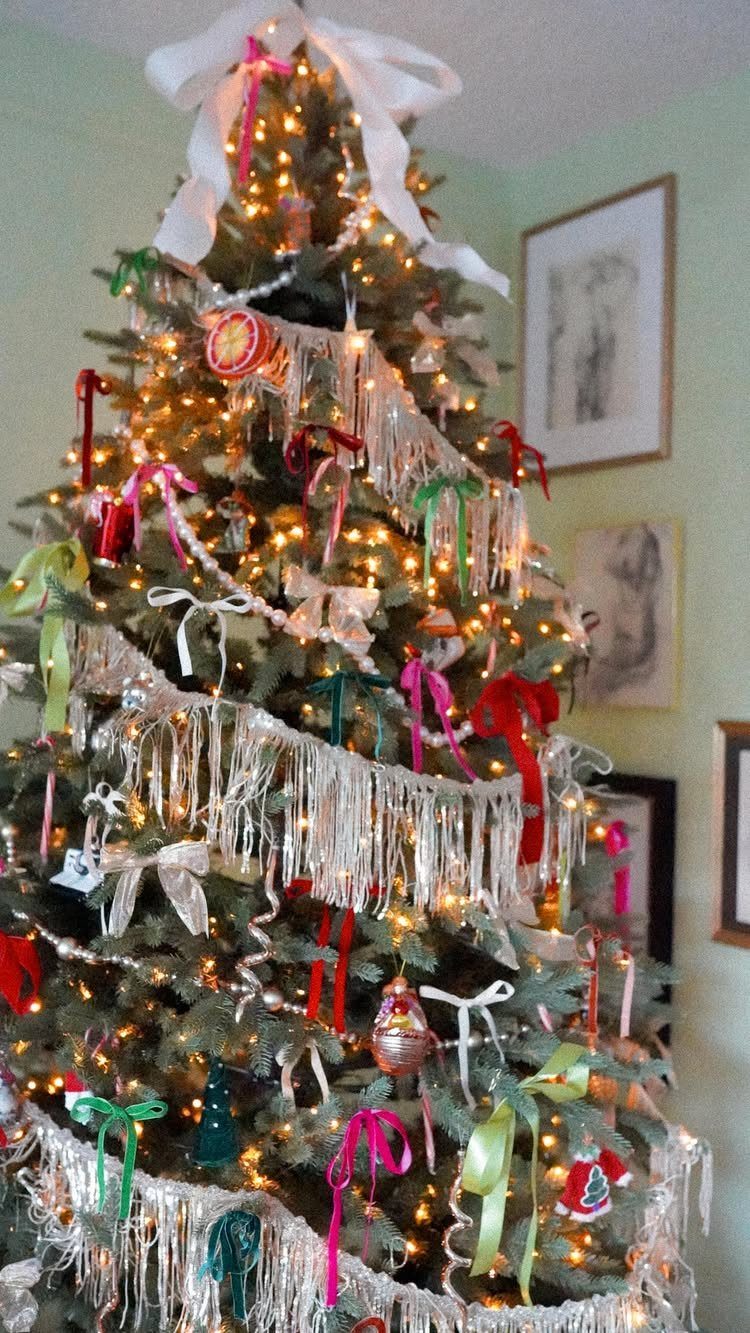 Decorated Christmas tree with silver tinsel, colorful ribbons, and warm white lights.