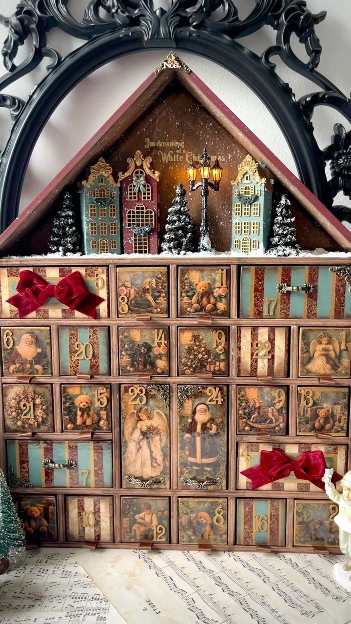 Vintage wooden advent calendar with numbered drawers and a miniature Christmas village on top.