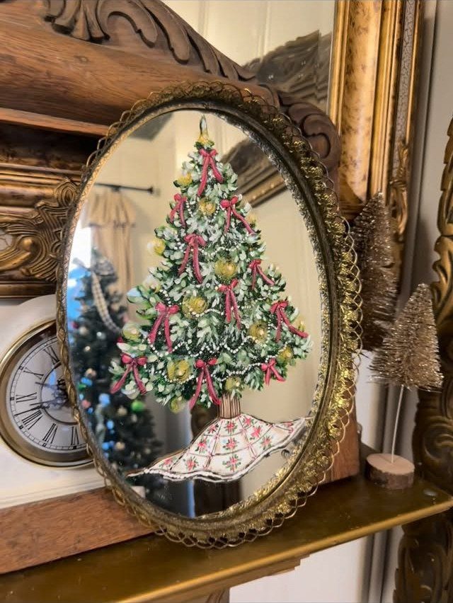 Oval gold-framed 3D Christmas tree art with red bows on a mirrored background.