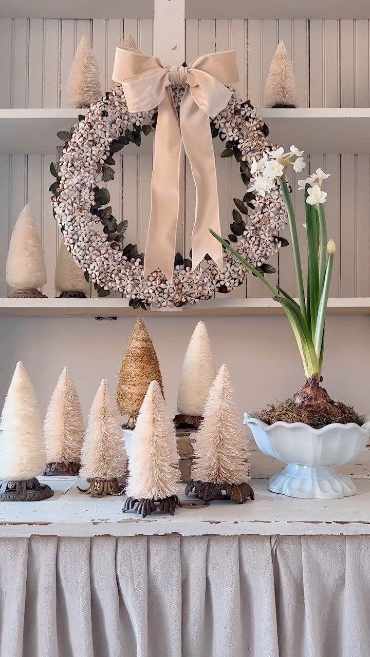 Vintage Christmas wreath with a large beige bow and small bottle brush trees.