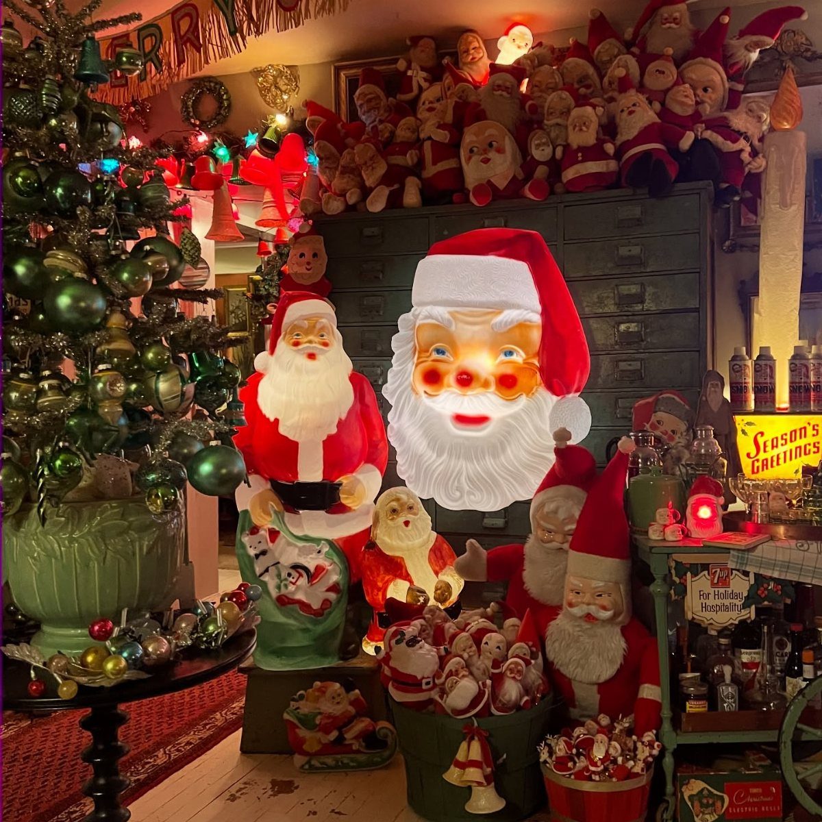 Various vintage Santa figurines and a decorated Christmas tree in a festive room.