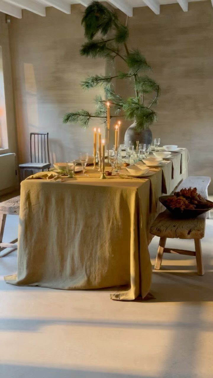 9 Wabi Sabi Dining Table Ideas for an Organic, Lived-In Space 5 Dining table with yellow linen cloth, tall candles, and a rustic wooden stool.