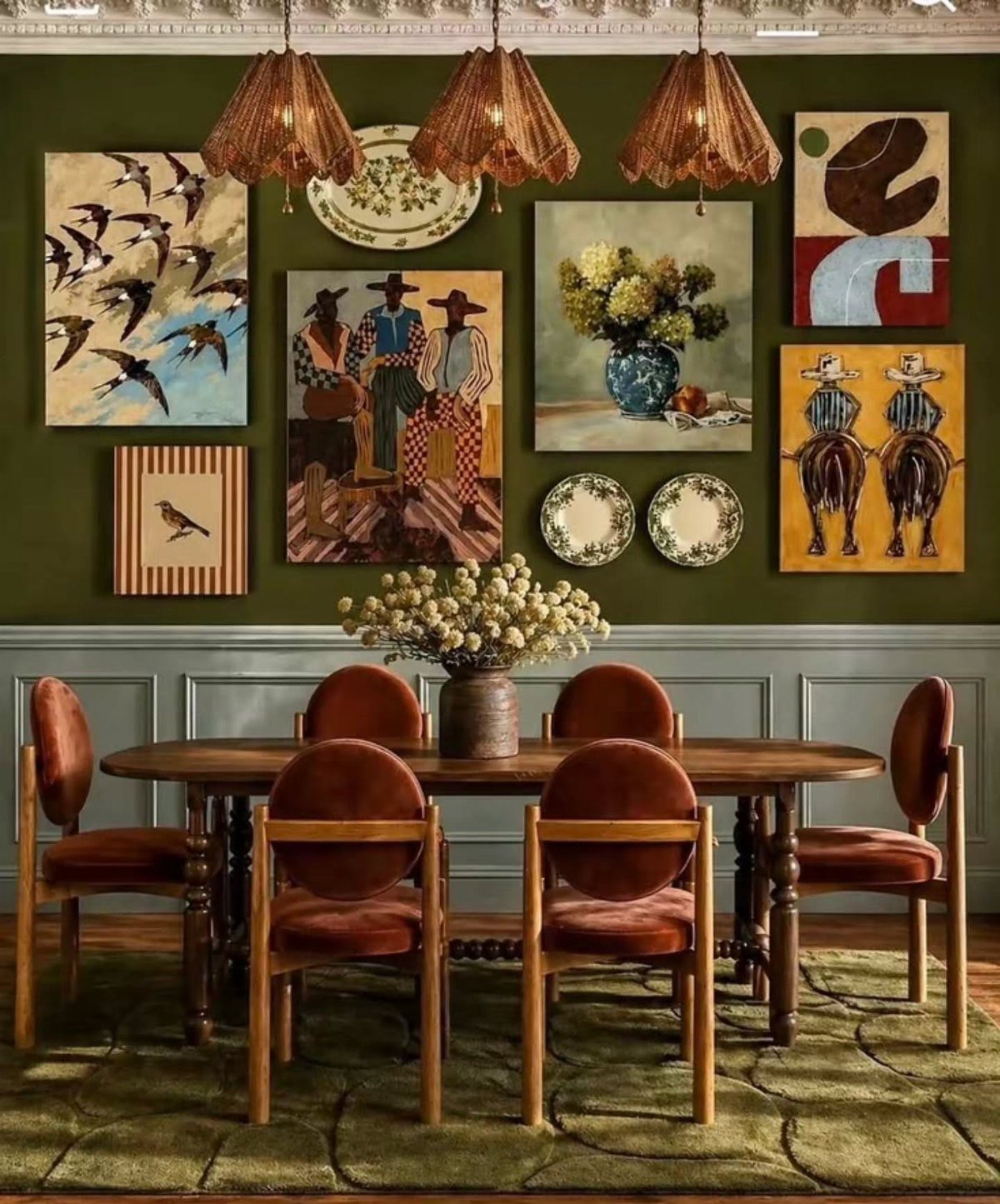 Dining room with olive green walls and a gallery of traditional art paintings.