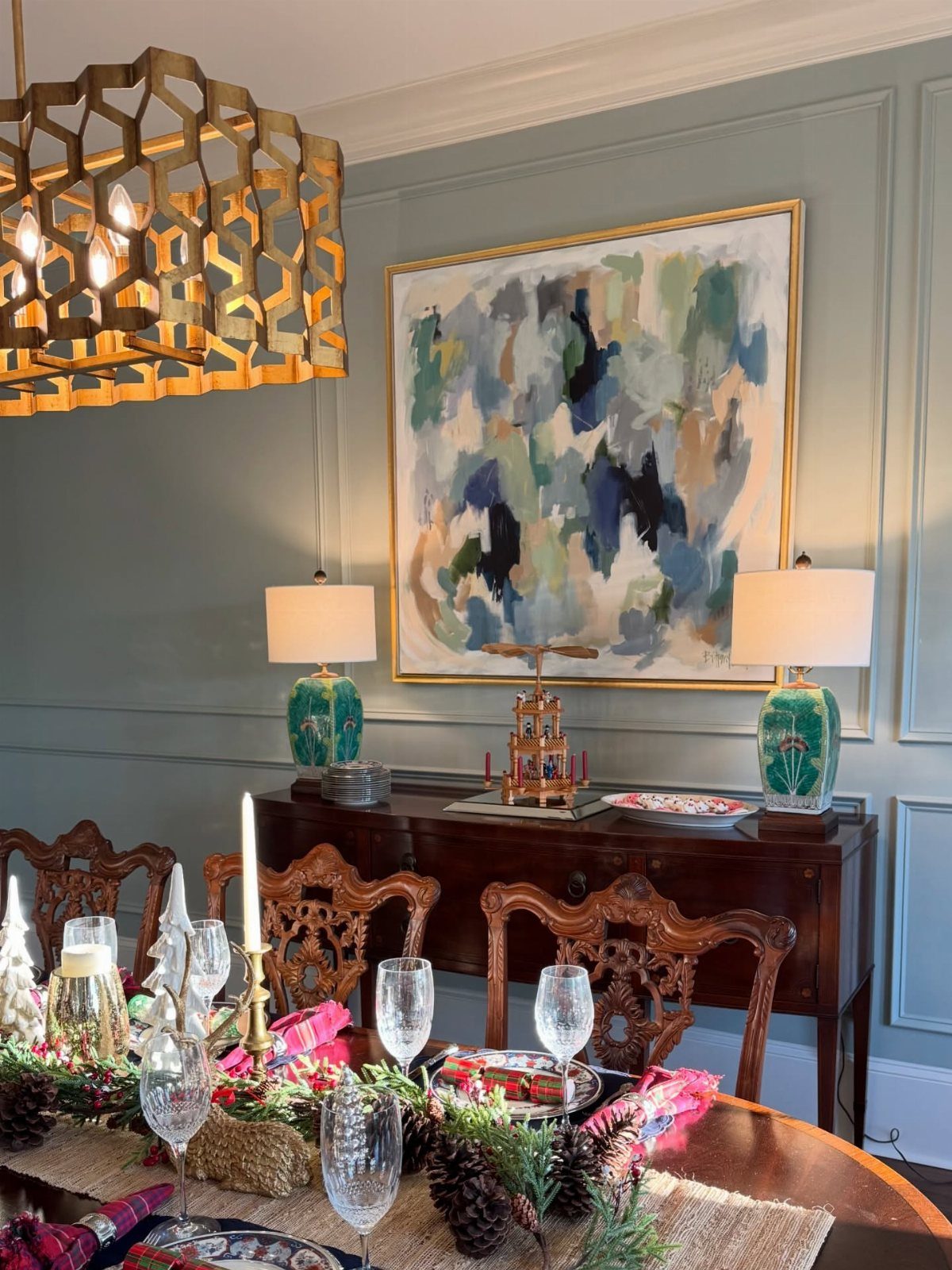 Abstract painting in gold frame hanging above a sideboard in a traditional dining room.