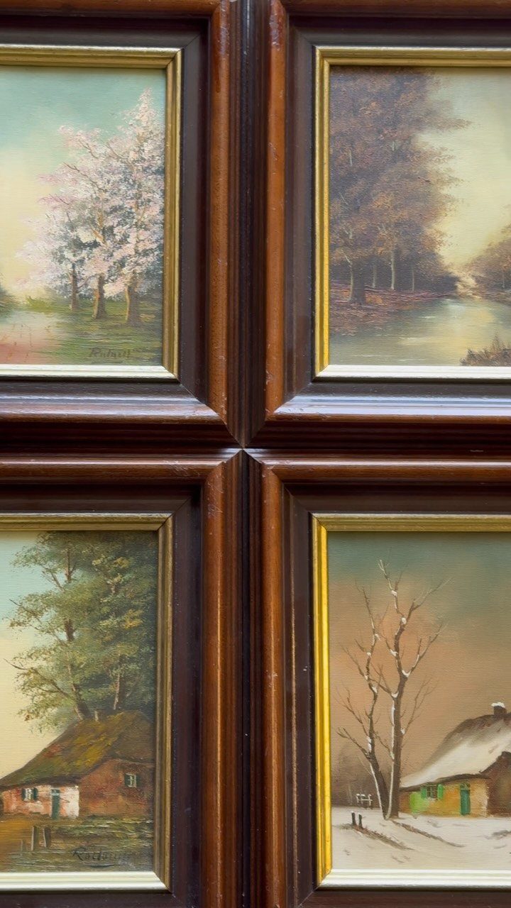 Four traditional landscape paintings in gold and wood frames on a paneled wall.