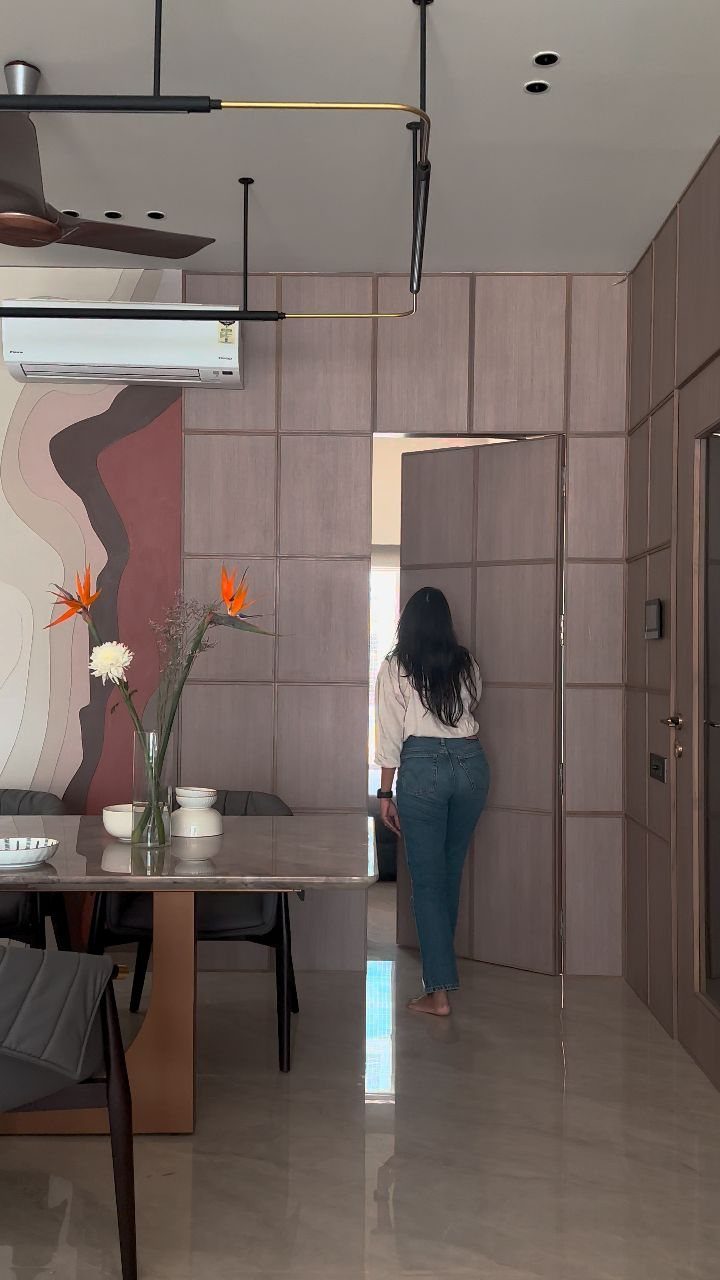 Woman standing in a doorway of a room with mauve square wood wall paneling